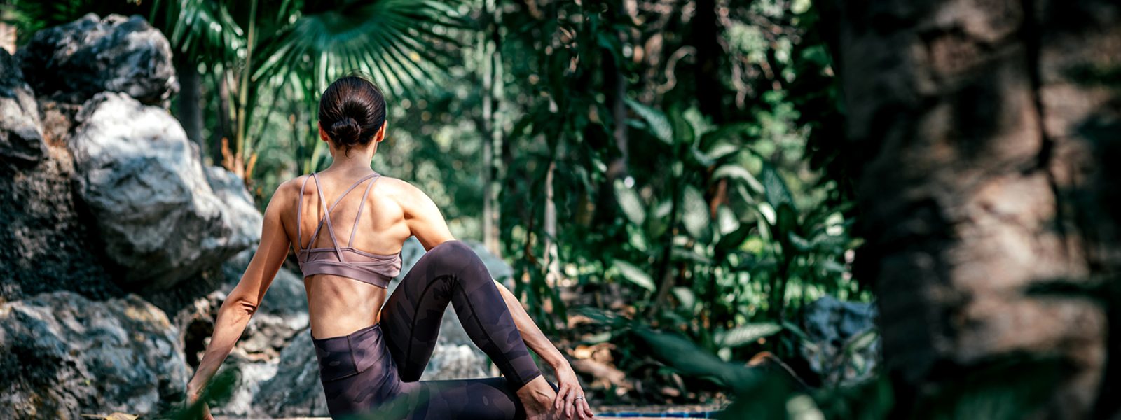 Relax your mind. Full-length shot of caucasian woman sitting in Seated Twist pose, Ardha Matsyendrasana while practicing yoga outdoors, in a garden. Healthy lifestyle and relaxation concept